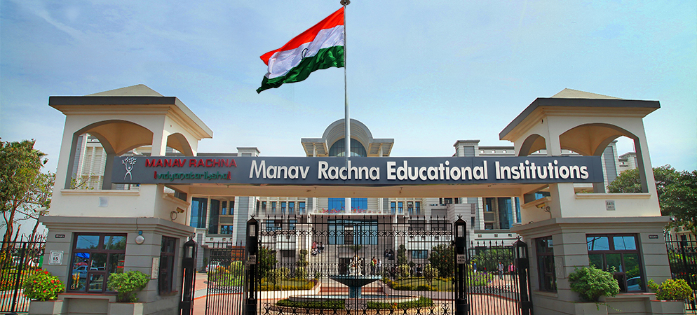 Main entrance of Manav Rachna Educational Institutions with a large Indian flag hoisted above and grand academic buildings in the background.