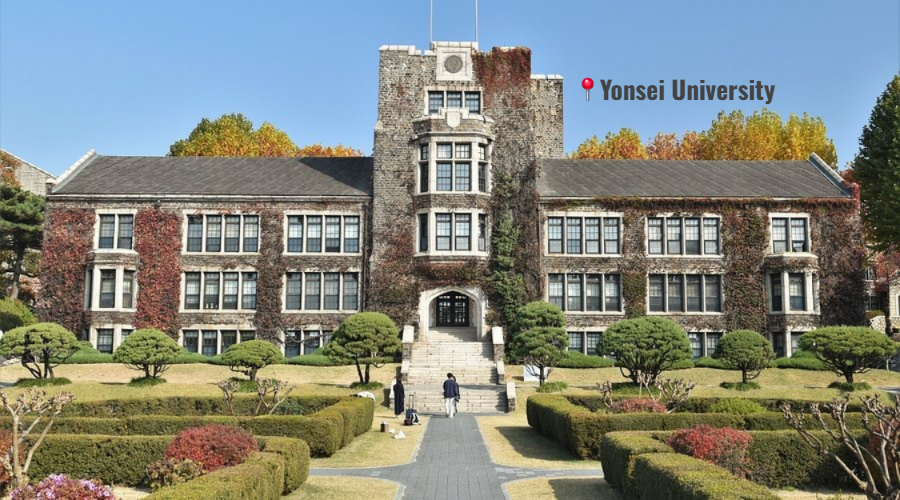 Aerial view of Yonsei University's Sinchon campus, showcasing its iconic Gothic architecture and lush green spaces, with students walking across the campus grounds.